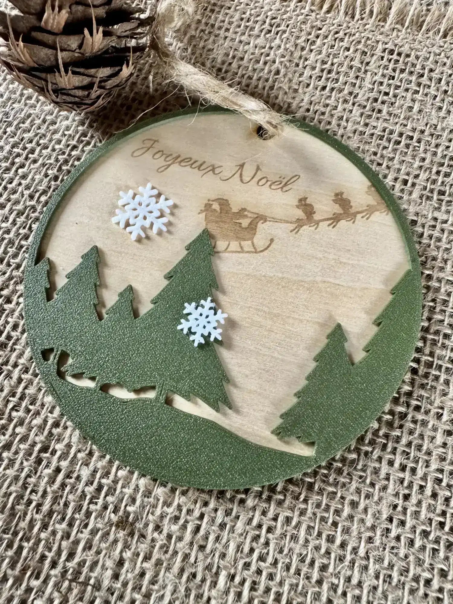 Boule de noel en bois gravée avec le texte Joyeux Noël, des sapins en premier plan et des flocons imprimés en PLA Biodégradable