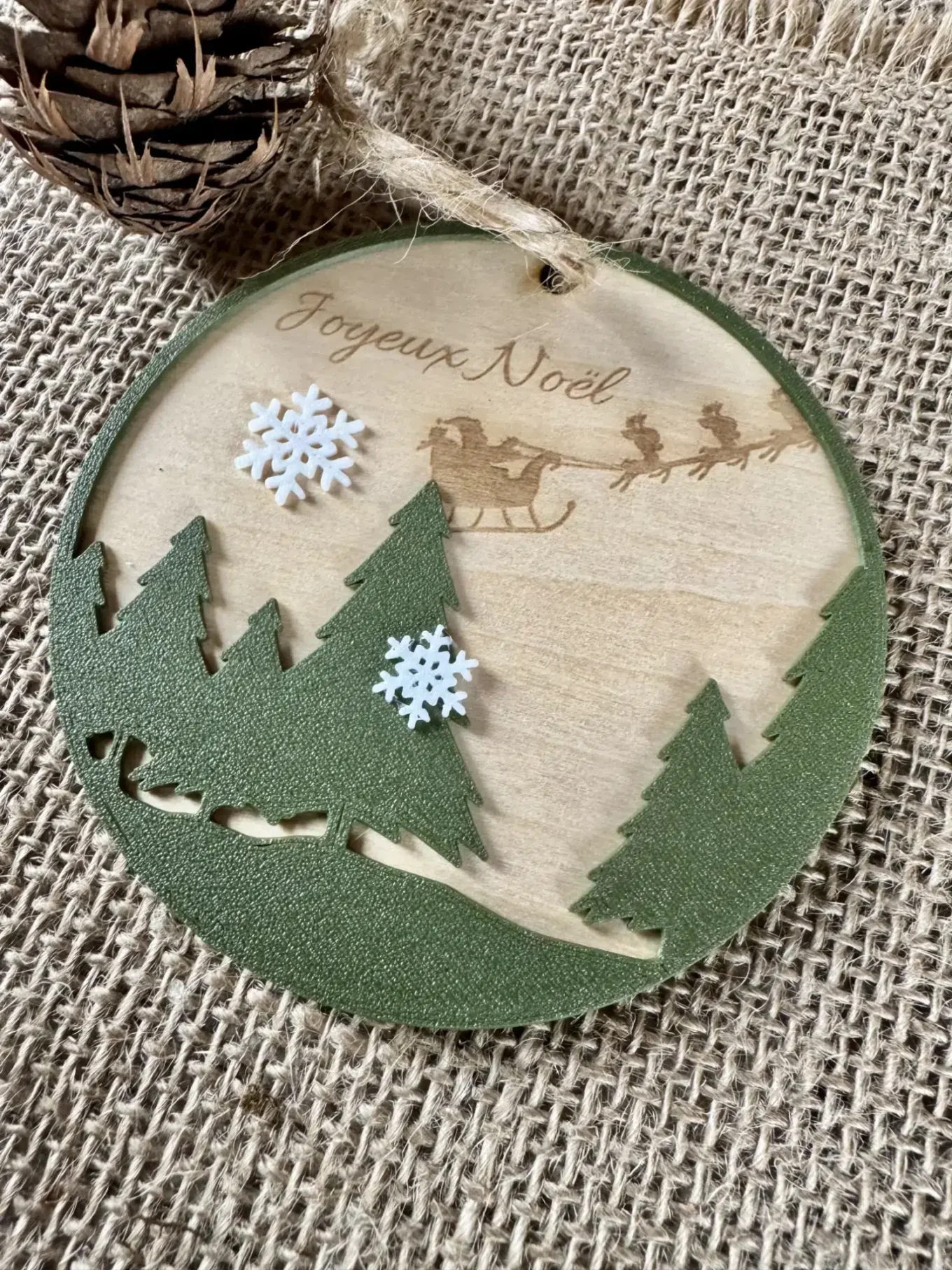 Boule de noel en bois gravée avec le texte Joyeux Noël, des sapins en premier plan et des flocons imprimés en PLA Biodégradable